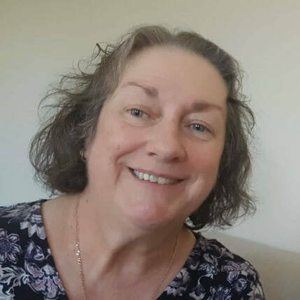 Head shot of Anne Smith smiling at the camera in floral dress.