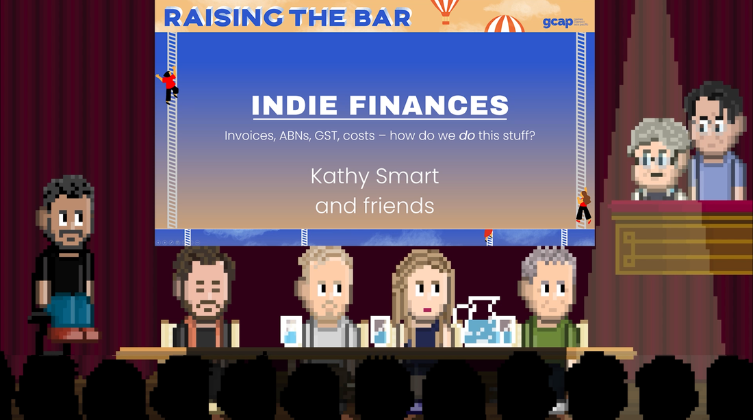 4 people sit at a table on a stage with glasses of water and theatre curtains closed behind them.  On one side an interviewer sits on a stool.  On the other side two more people stand.  Above their heads is a powerpoint presentation saying Indie Finances, Kathy Smart and Friends.